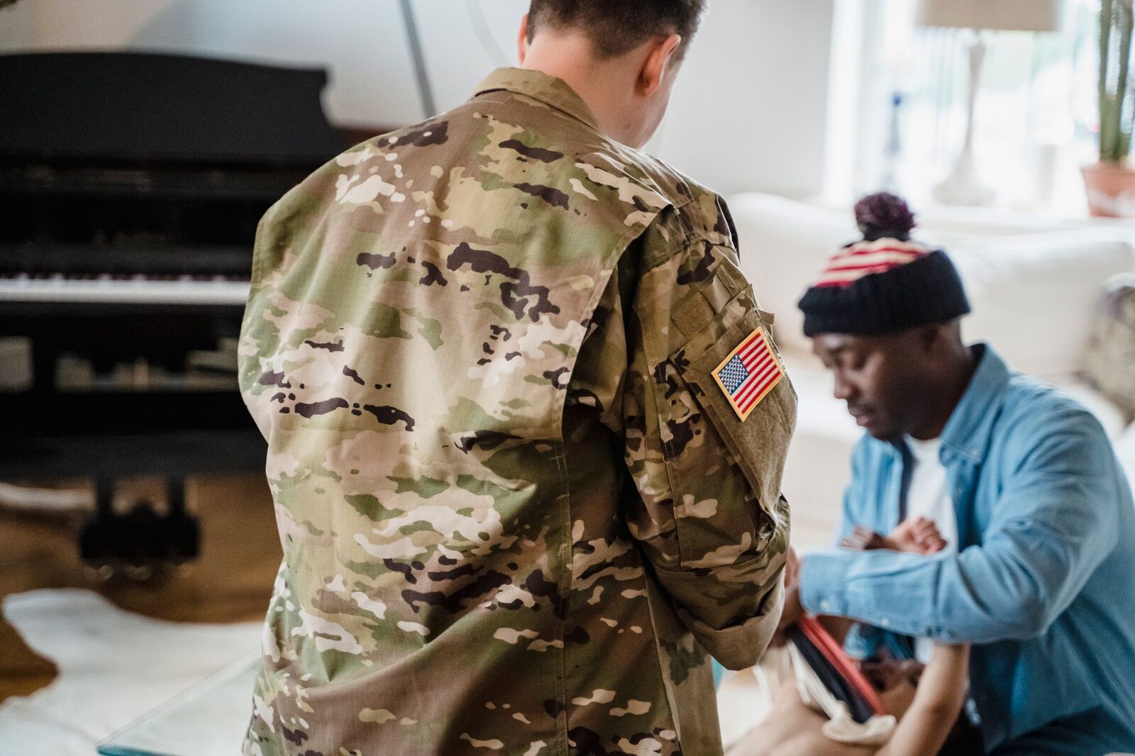 A soldier in camouflage uniform interacts with family at home, evoking themes of service and togetherness.